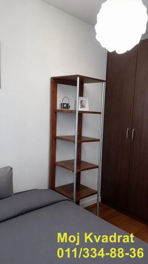 Spavaća soba sa krevetom, drvenom policom i garderoberom.