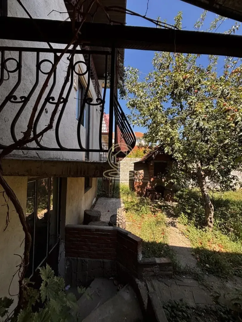 Eksterijer kuće sa dvorištem i balkonom sa kovanom ogradom.