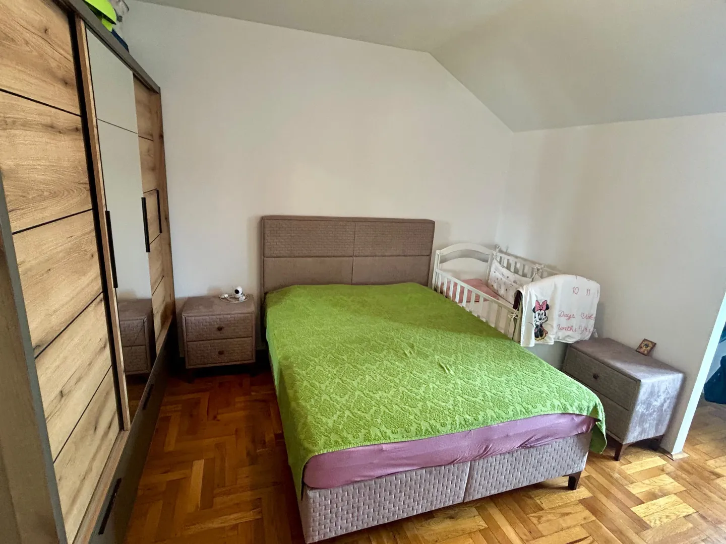Spavaća soba sa bračnim krevetom, garderoberom i dječijim krevetcem.