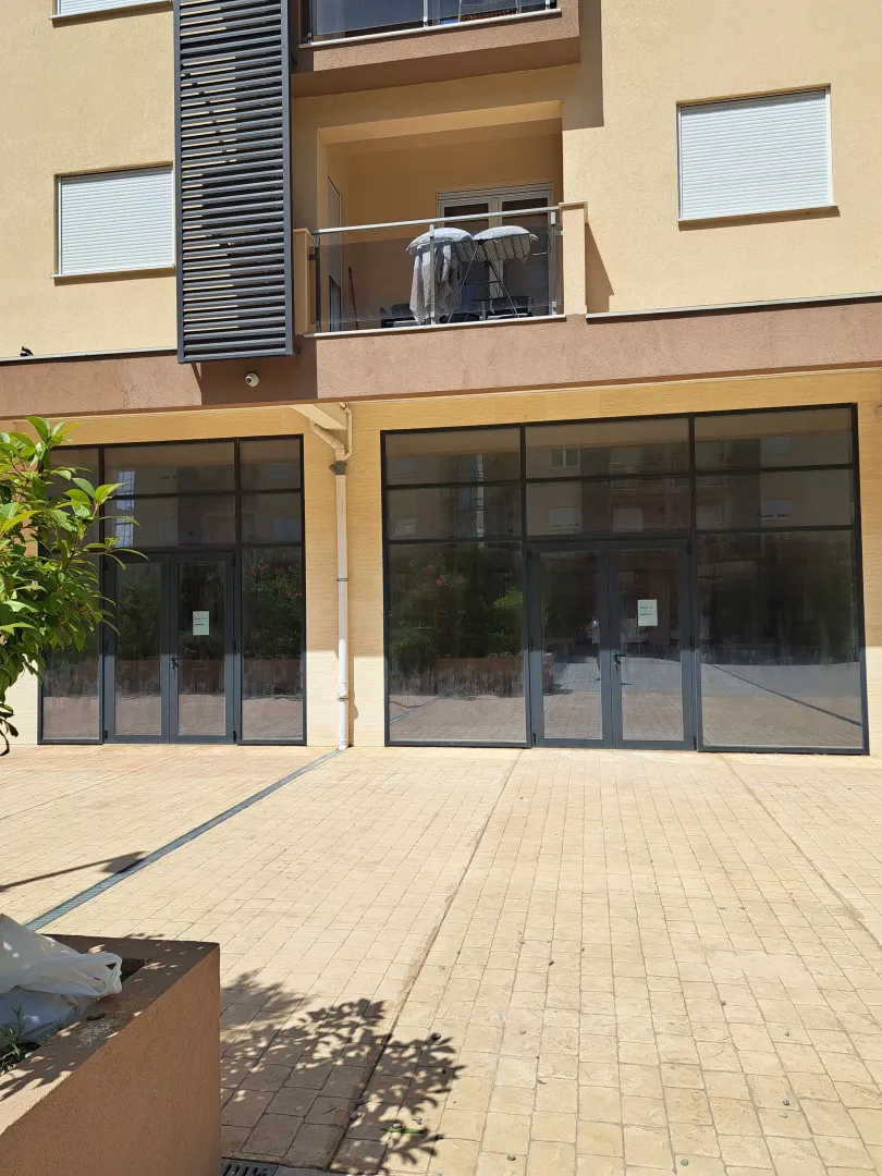 Exterior of a ground-floor commercial space in a building with a paved plateau in front.