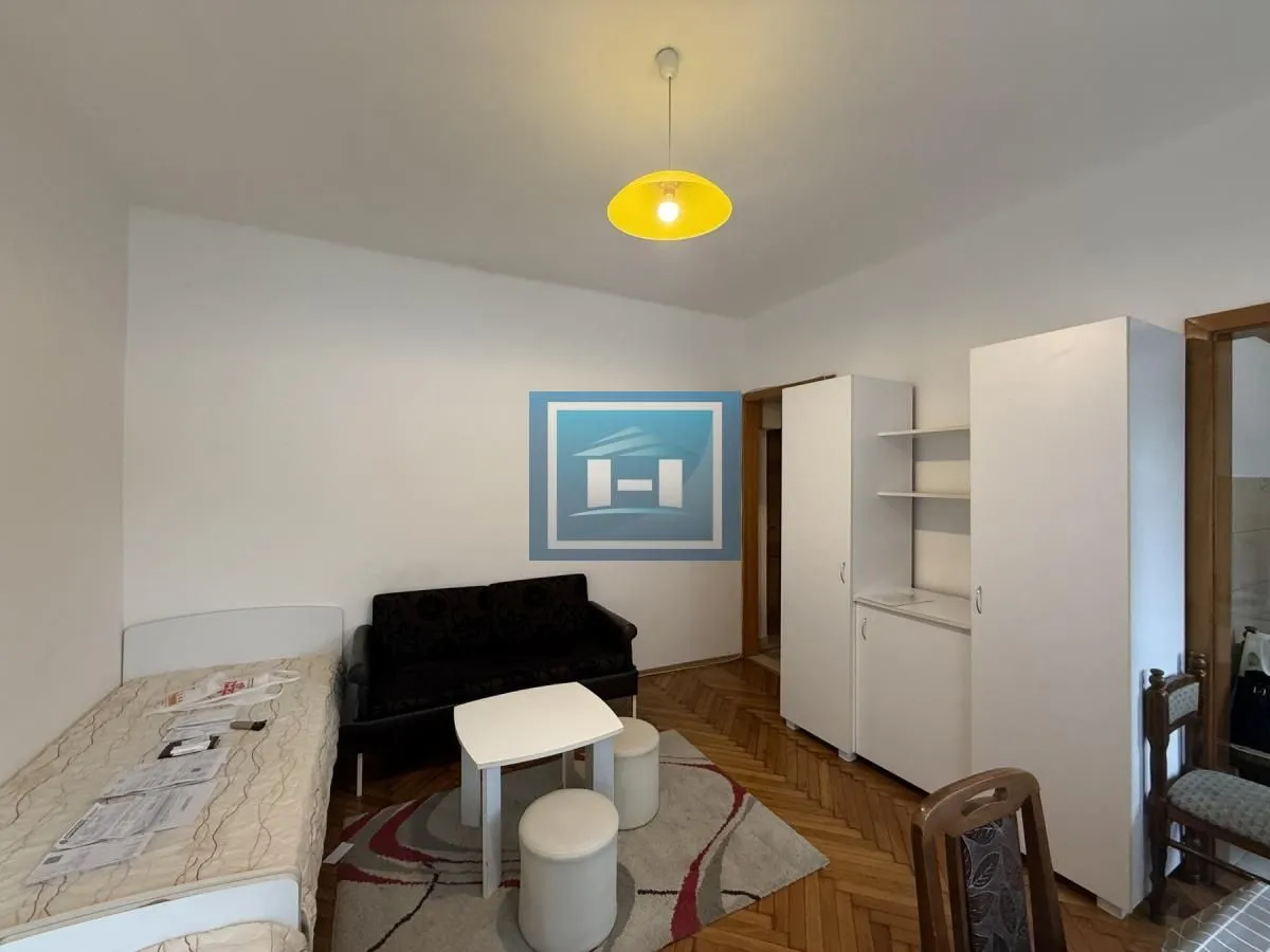 Small bedroom with a bed, sofa, wardrobe, and parquet flooring.