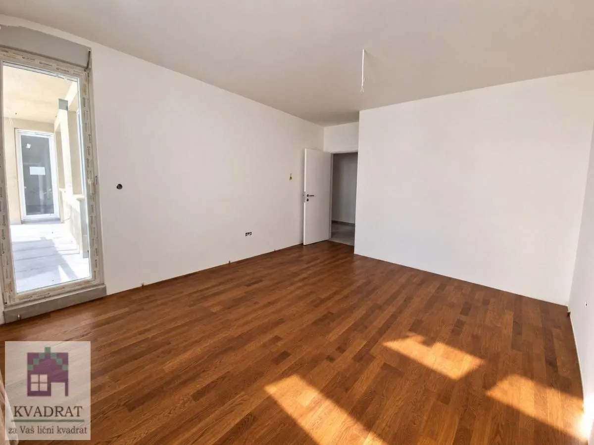 Empty room with wooden flooring and access to the terrace.