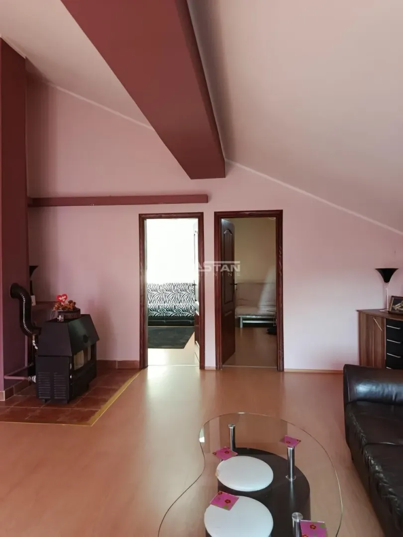 Living room with a sofa, wood stove, and doors leading to other rooms.
