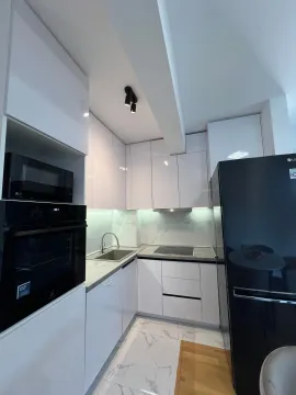 Moderna bijela kuhinja sa ugradnim aparatima i crnim frižiderom. - image 10