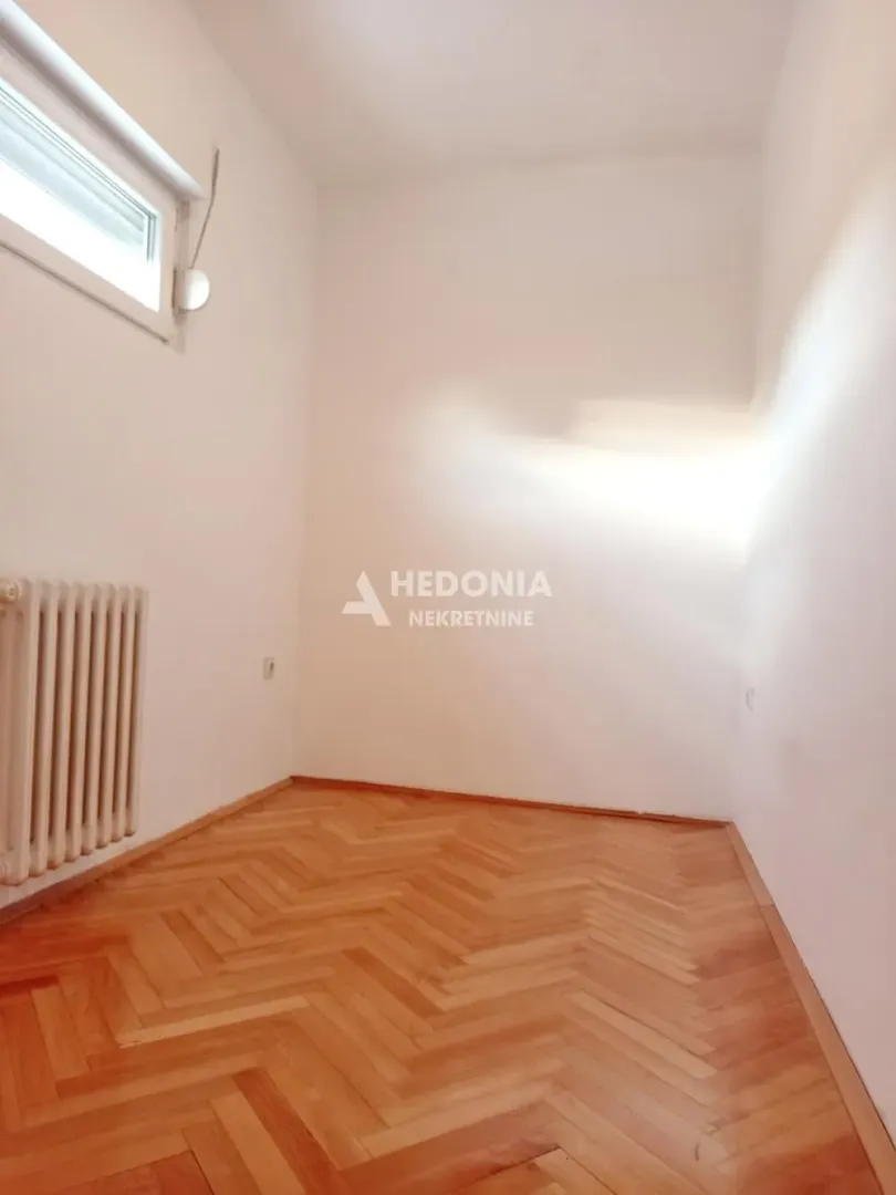 Empty room with parquet flooring and a radiator.