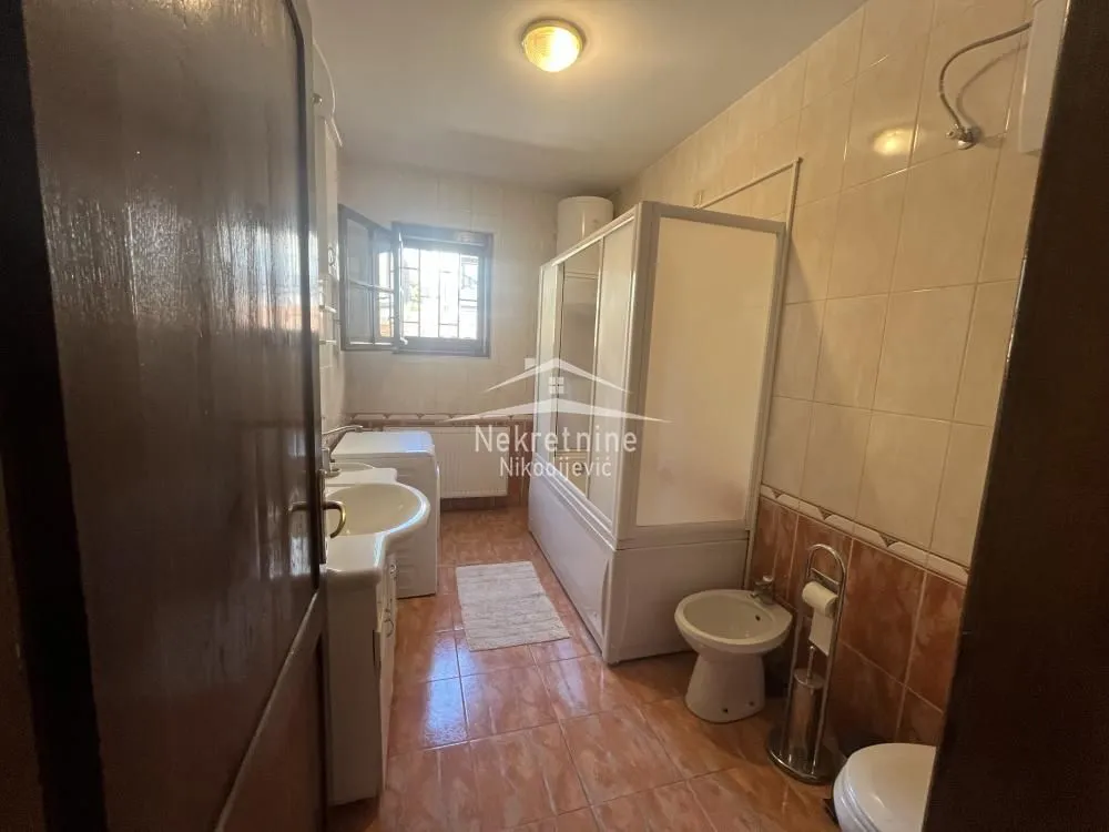 Bathroom tiled with ceramic tiles featuring a shower cabin, washbasin, and toilet facilities.
