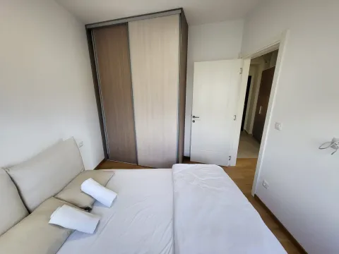 Svjetla spavaća soba sa bračnim krevetom, velikim garderoberom i bijelim vratima. - image 10