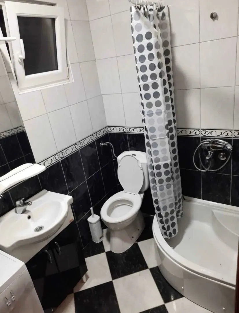 Small bathroom with a sink, toilet, and a shower cabin with a curtain.