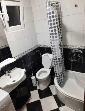 Small bathroom with a sink, toilet, and a shower cabin with a curtain. - image 6