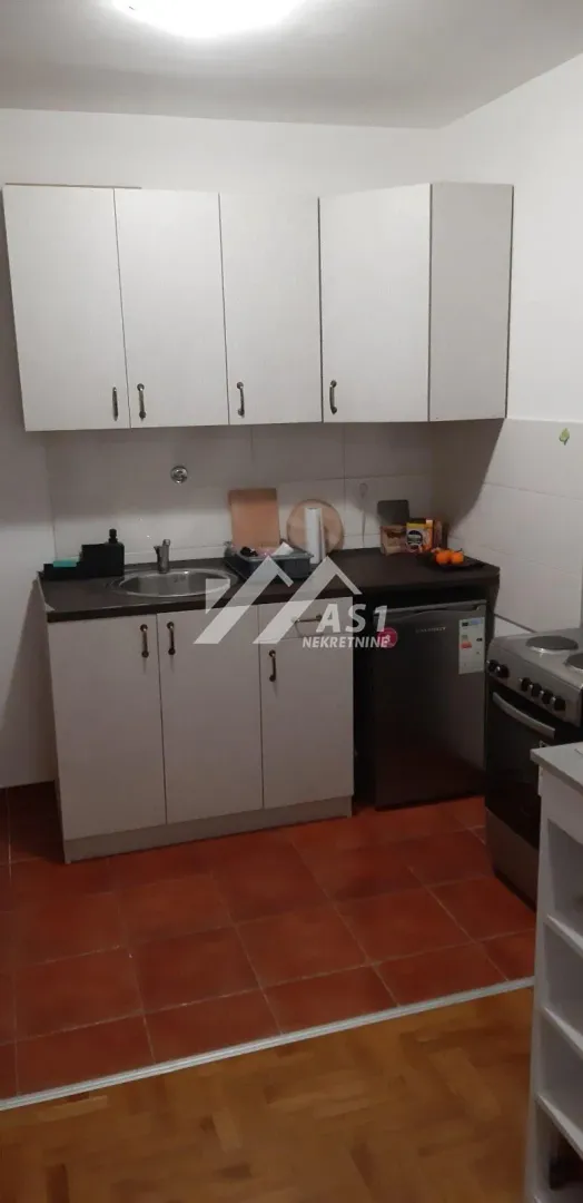 Smaller kitchen with lower and upper cabinets and a stove.