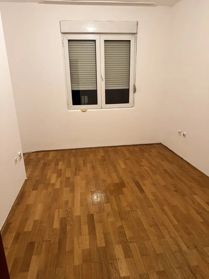 Empty room with parquet flooring and a window.