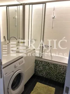 Bathroom equipped with a bathtub, washbasin, and washing machine. - image 4