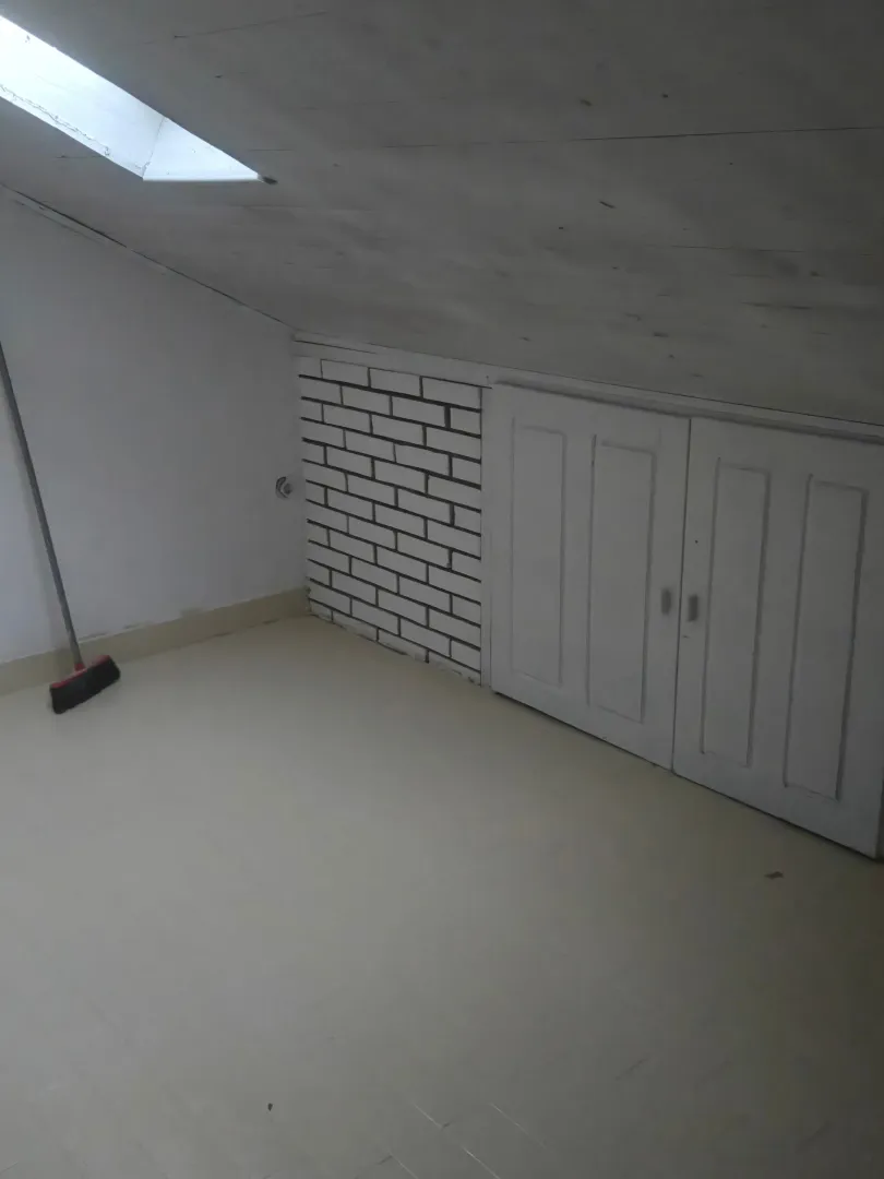 Potkrovlje sa kosim plafonom, krovnim prozorom i ugradnim ormarima.