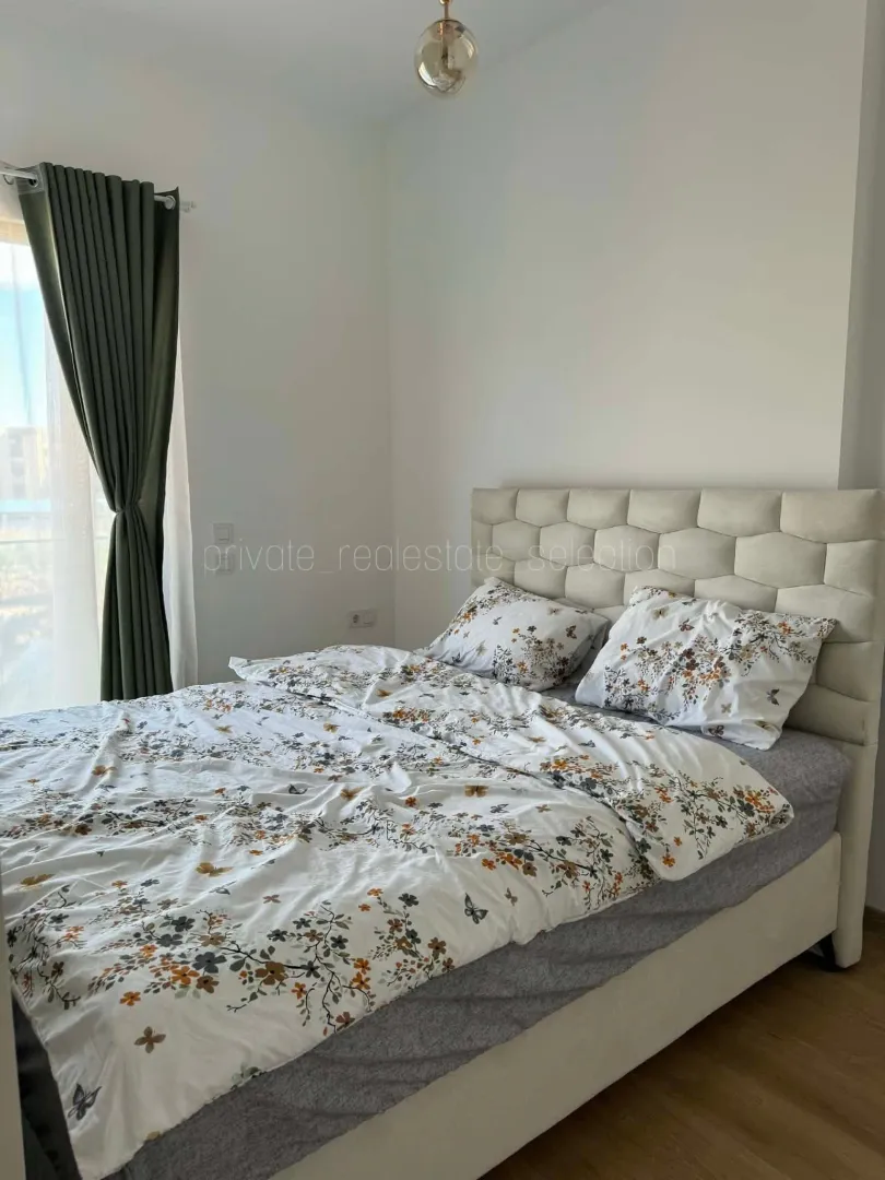 Furnished bedroom with a double bed and green curtains.