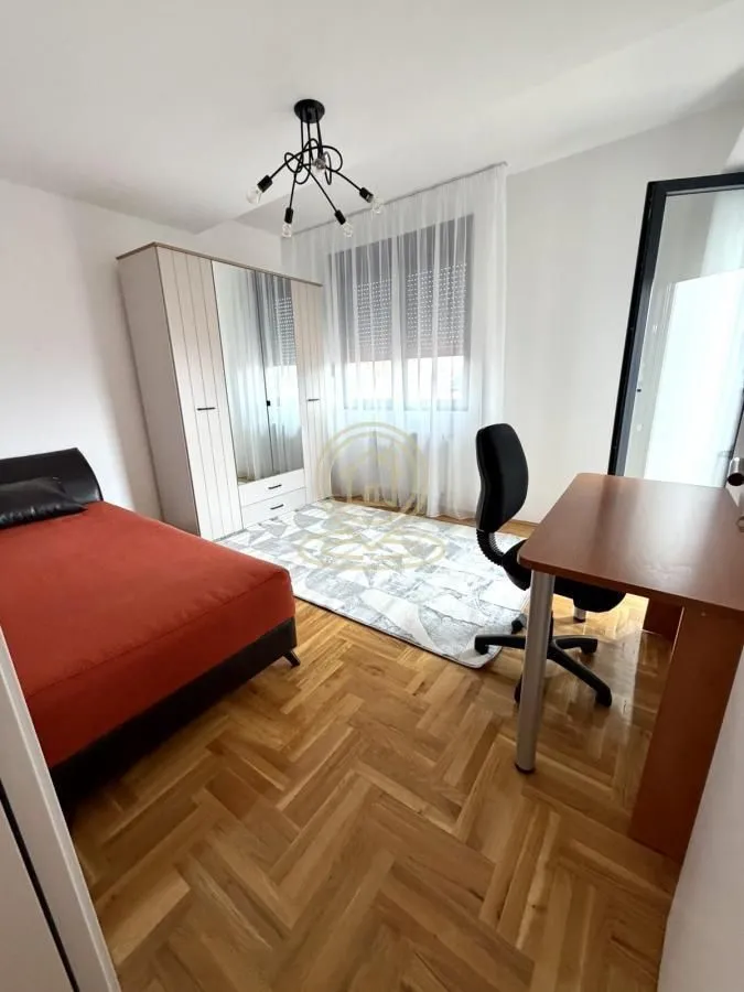 Furnished bedroom with a bed, desk, and wardrobe.