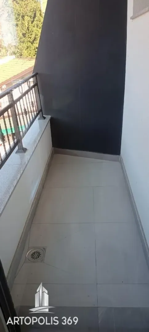 Prazan balkon sa podnim pločicama i ogradom.