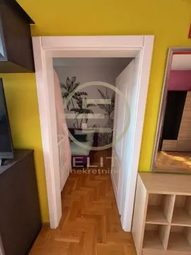 Pogled iz hodnika kroz vrata na dečiju spavaću sobu sa krevetom i tapetom sa motivom palma. - image 7