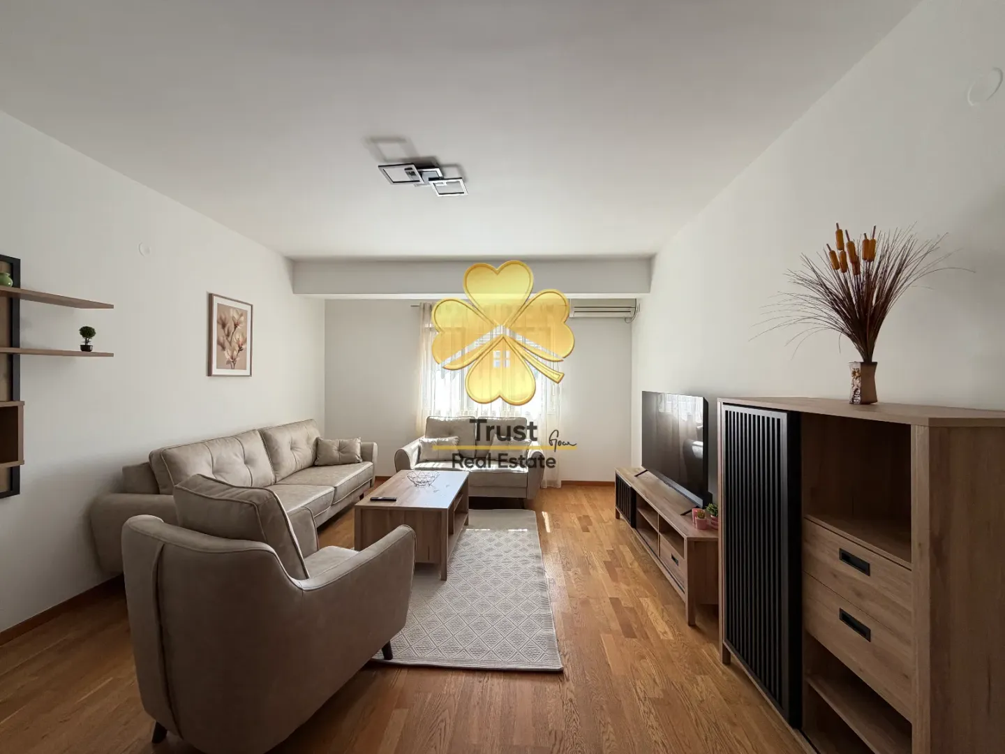 Spacious and bright living room with sofa set and wooden furniture.