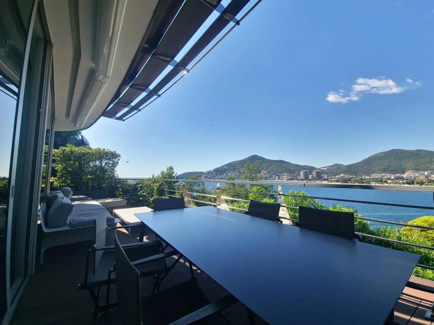 Spacious terrace with a dining table and views of the sea and mountains.