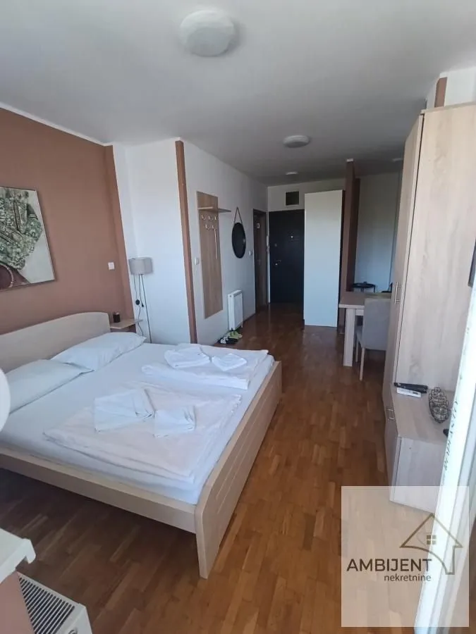 Nameštena spavaća soba sa bračnim krevetom i drvenim podom.