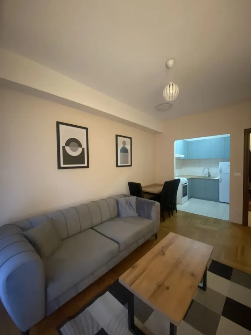 Bright living room with a grey sofa and dining area in the background.
