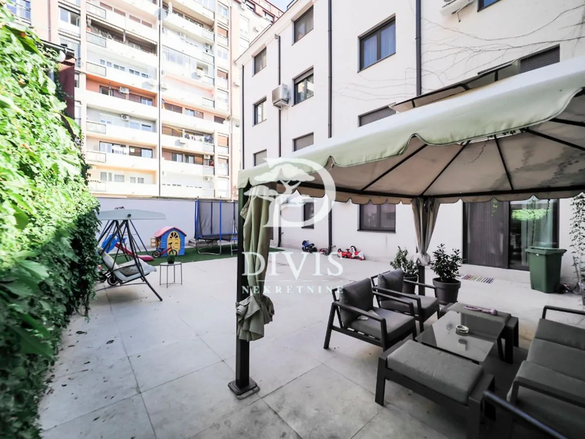 Building courtyard with seating furniture and children's playground equipment.