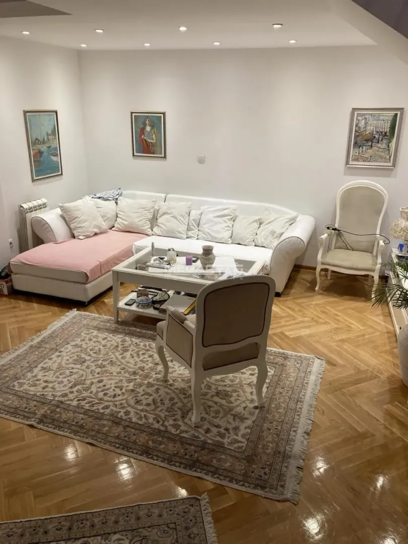 Dnevna soba sa garniturom, stočićem i parketom na podu.