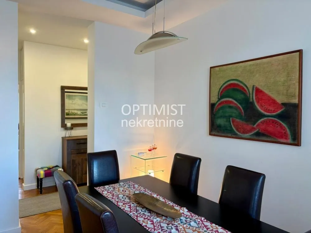 Dining area with a black table, chairs and an art painting on the wall.