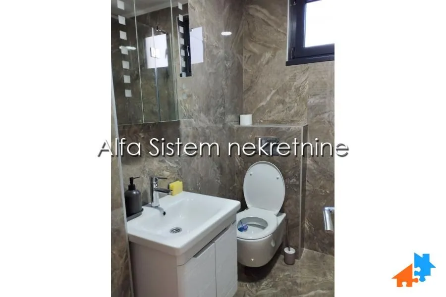 Smaller bathroom tiled with ceramic tiles, featuring a sink and a toilet.