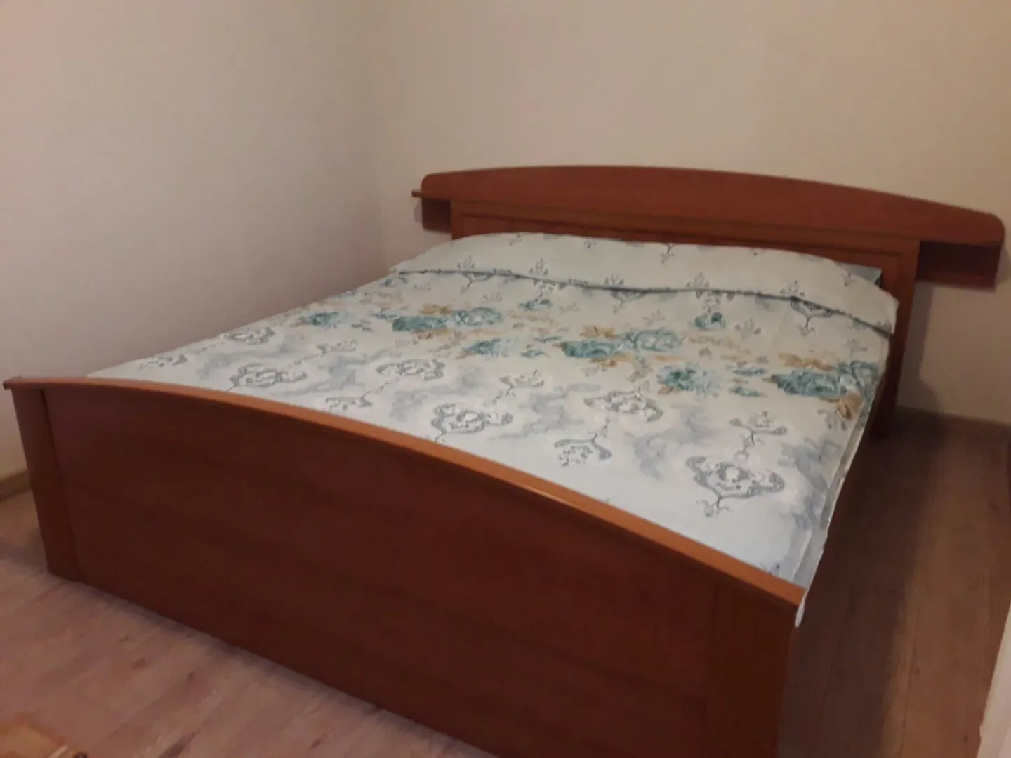 A simple bedroom featuring a large wooden bed with patterned bedding.