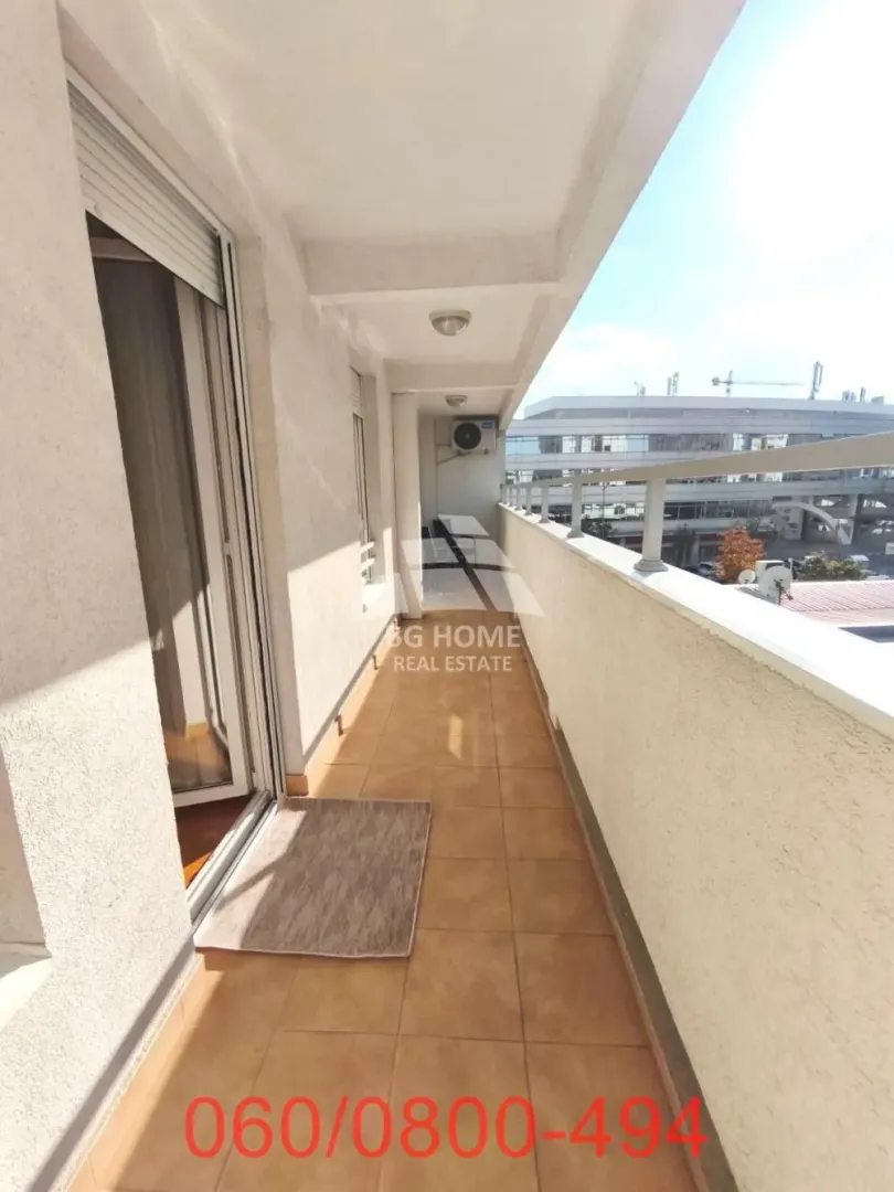 Prostrani popločani balkon sa ogradom i pogledom na okolinu.