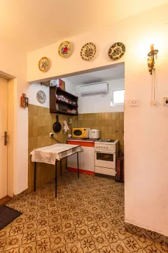 Manja kuhinja sa trpezarijskim stolom i ukrasnim tanjirima na zidu. - image 36