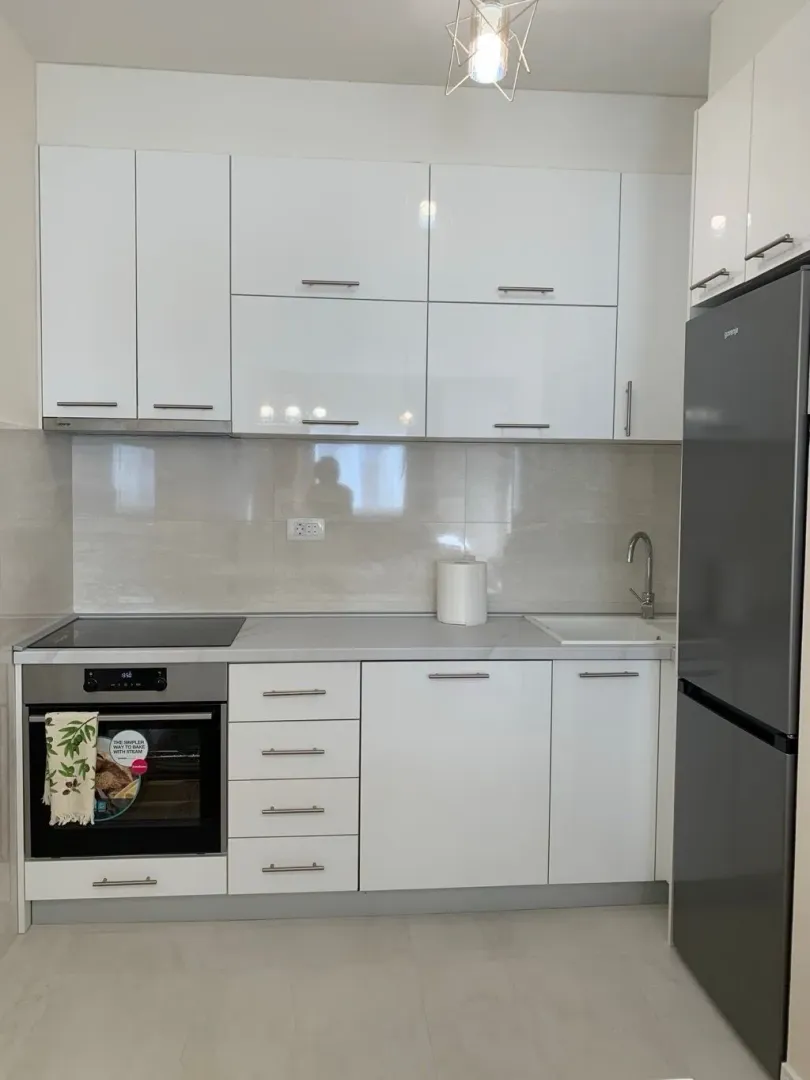 Moderna bijela kuhinja sa ugrađenim aparatima i frižiderom.