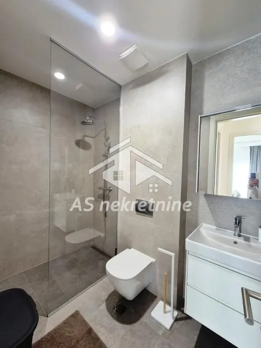 Modernly equipped bathroom with a glass walk-in shower, wall-hung toilet, and vanity sink.