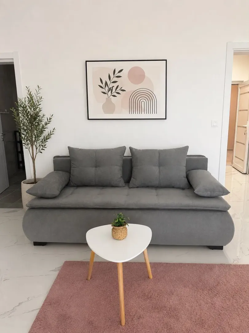 Bright living room with a grey-blue sofa, white coffee table, and decorative wall art.