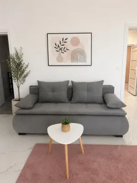 Bright living room with a grey-blue sofa, white coffee table, and decorative wall art. - image 3