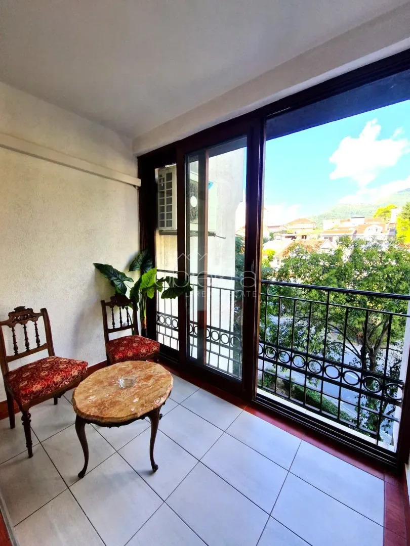 Covered balcony with seating furniture and a view of the surroundings.