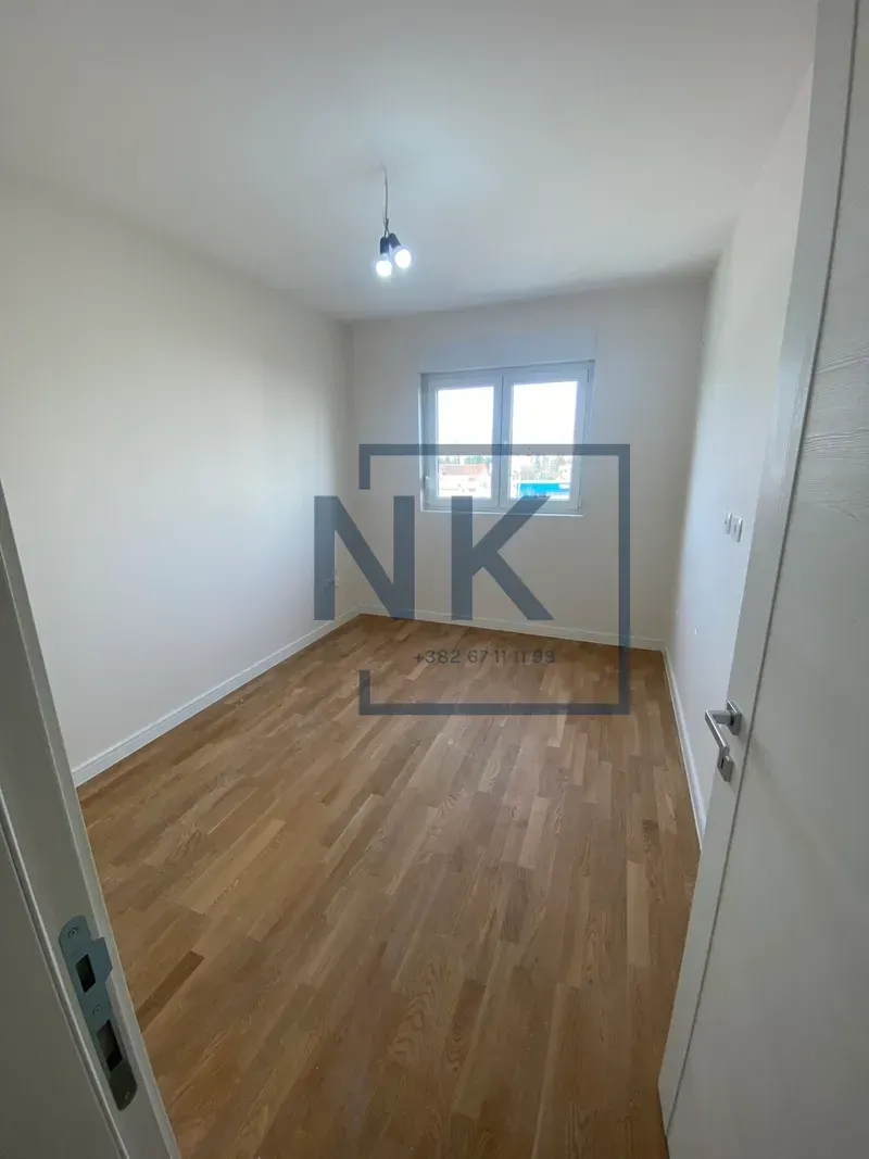 Prazna soba sa parketom i bijelim zidovima.