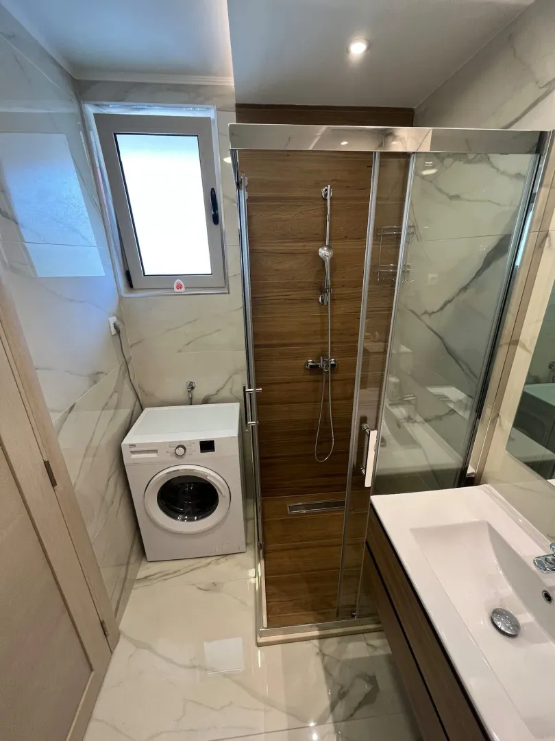 Modern equipped bathroom with a shower cabin and washing machine.