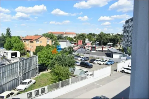 View from the window overlooking surrounding buildings, parking lot, and greenery. - image 16
