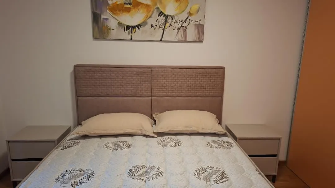 Namještena spavaća soba sa bračnim krevetom i noćnim stočićima.