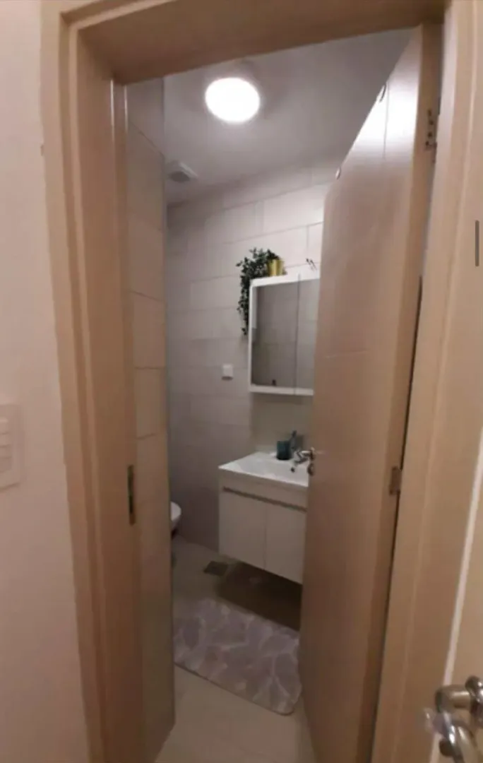 View through an open door into a modern bathroom with a vanity sink and mirror.