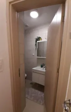 View through an open door into a modern bathroom with a vanity sink and mirror. - image 5