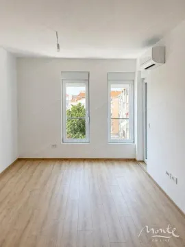 Prazna svijetla soba sa drvenim podom, bijelim zidovima i klima uređajem. - image 2
