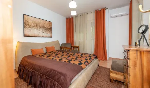 Furnished bedroom with a double bed, dresser, and orange curtains. - image 7