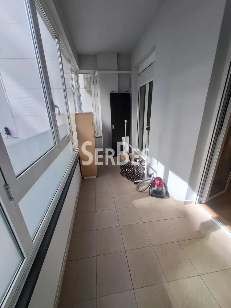 Enclosed balcony with ceramic floor tiles and windows along the entire wall.