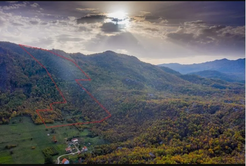 Vazdušni snimak brdovitog predjela sa označenim granicama parcele pod sunčevim zracima.