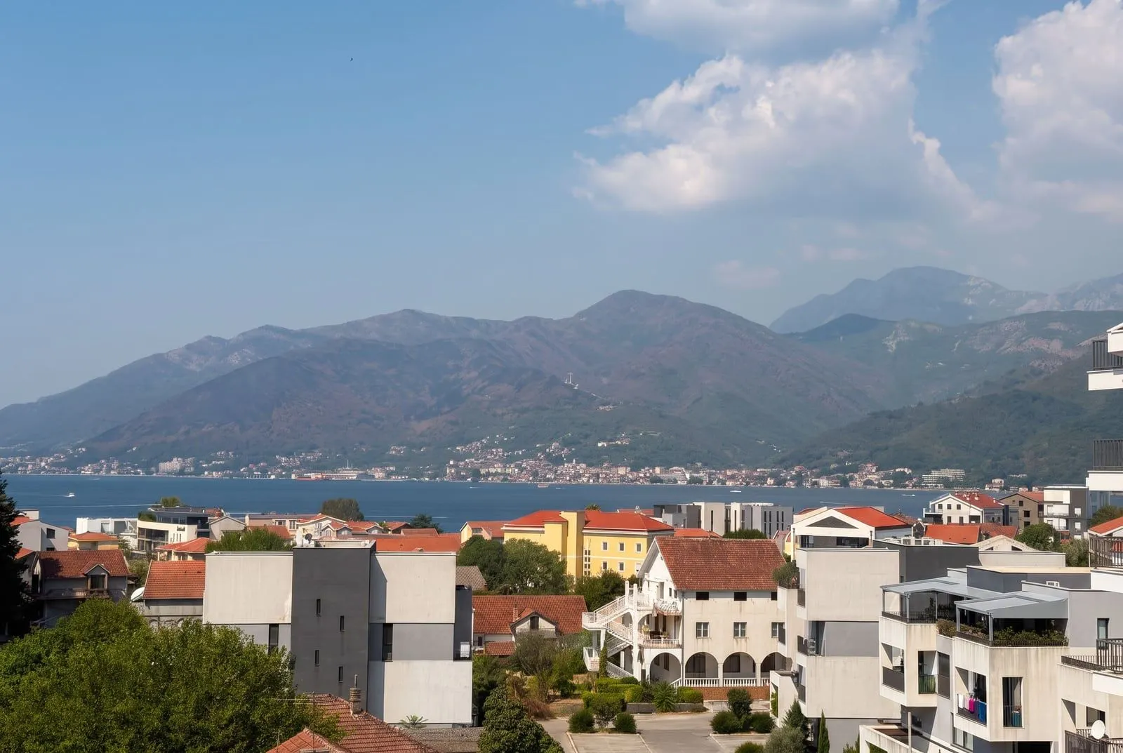Pogled na more, grad i planine u pozadini.