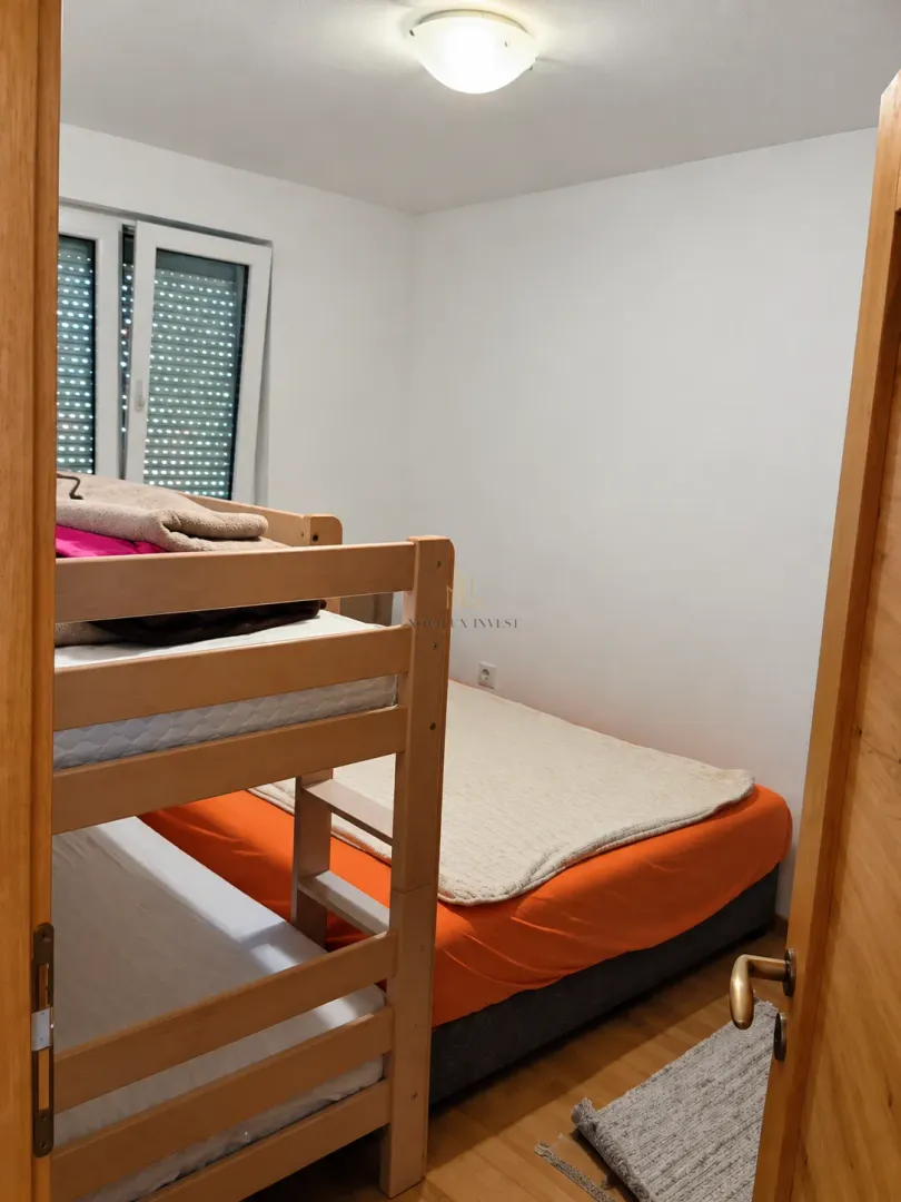View through the doorway into a small bedroom with a bunk bed and a double bed.