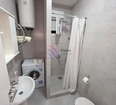 Compact bathroom with a shower enclosure, washbasin, and washing machine. - image 6